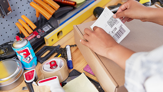 Paketschein wird auf einer Werkbank auf ein Paket geklebt