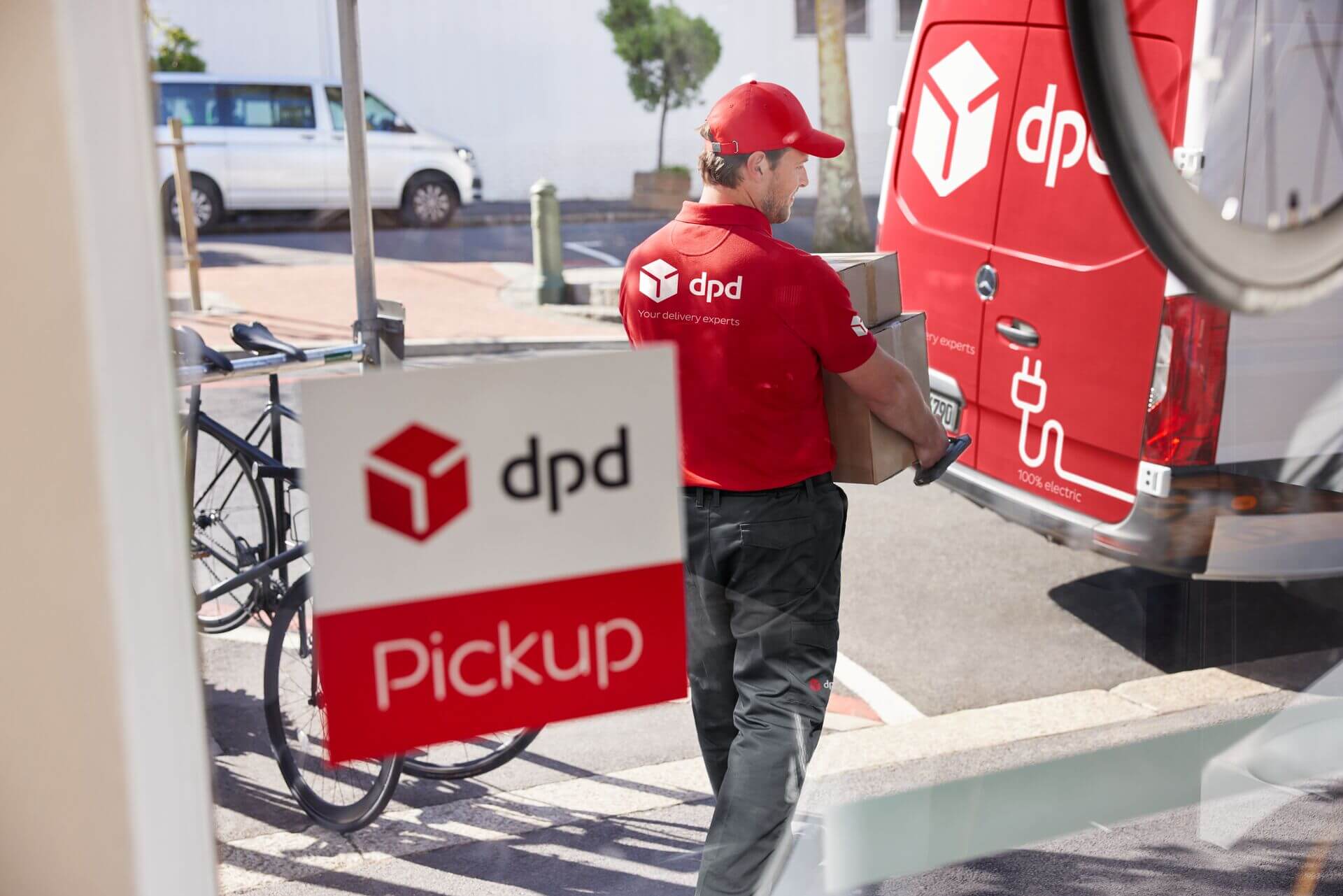 Kurier DPD z paczkami przy elektrycznym samochodzie dostawczym. Punkt odbioru DPD Pickup.