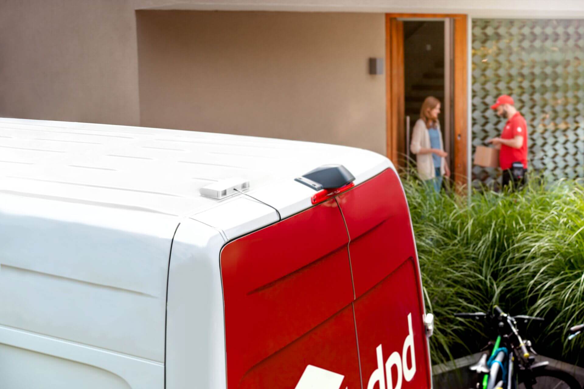 DPD electric car and courier delivering a parcel in the background (Indefinite photo license)